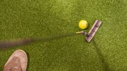 grüner kunstrasen, gelber golfball, golfschläger