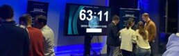 Teilnehmer bei einem Space Escape Event in München, Deutschland, konzentrieren sich auf einen Bildschirm, der einen Countdown anzeigt, während sie den richtigen Code eingeben müssen